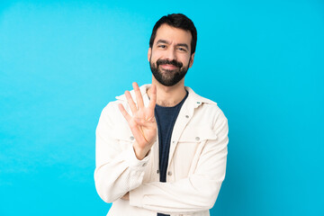 Young handsome man with white corduroy jacket over isolated blue background happy and counting four...