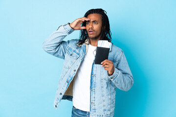 Young African American man with braids isolated on blue background in vacation with passport and...