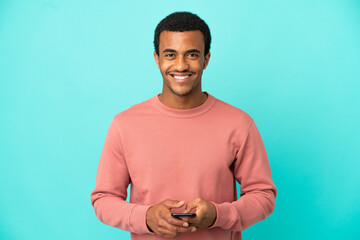African American handsome man on isolated blue background sending a message with the mobile