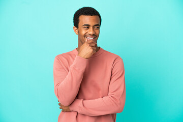 African American handsome man on isolated blue background looking to the side and smiling