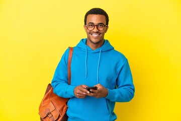 African American student man over isolated yellow background sending a message with the mobile