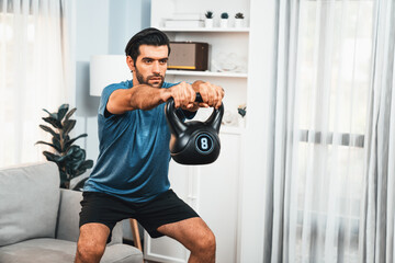 Athletic body and active sporty man doing squat with kettlebell weight for effective targeting...