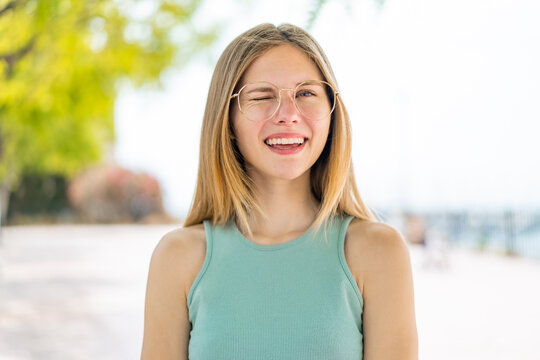Young blonde woman at outdoors With glasses and happy expression