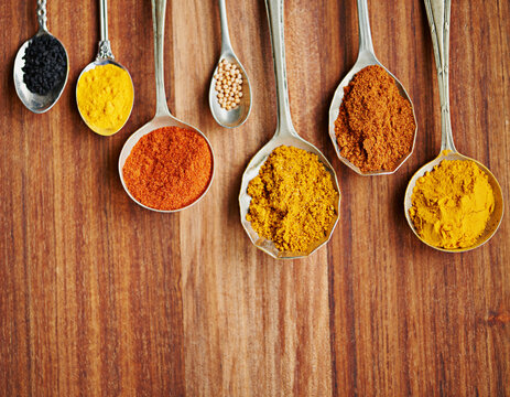 Spoons, spice and selection of flavor for seasoning on kitchen table, turmeric and paprika for meal. Top view, condiments and options for spicy cooking in Indian culture, cumin and food preparation