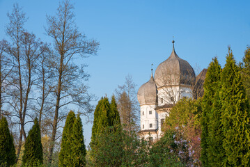 towers of Schwindegg water castle between thuja trees. blue sky background