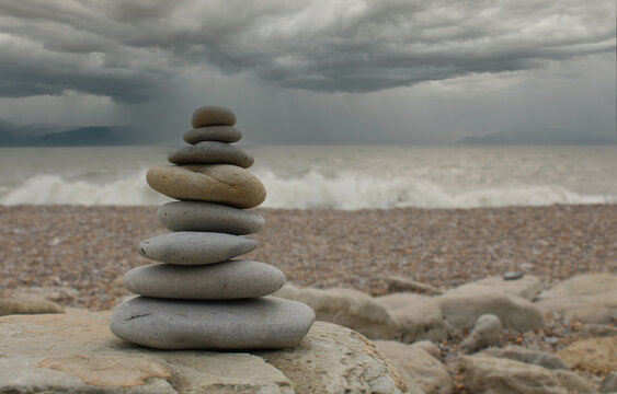 Pyramid of stones in the sand at the beach and waves	