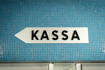 White Kassa sign on blue mosaic wall in Vienna