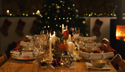 Dinner, table and Christmas in home with candles at night, love and celebration for holidays. Feast, dining and house or dark with lights for xmas, flowers and bowls or wine glasses at fireplace