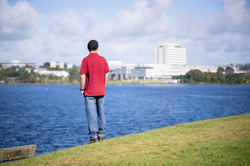 Man looking at the views across lake Pupuke. North Shore Hospital in the distance. Takapuna, Auckland. - 790666130