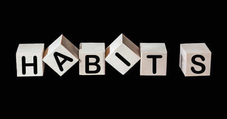 The word Habits written on wooden cubes and black background