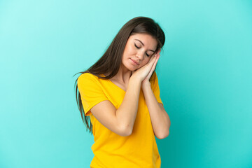 Young caucasian woman isolated on blue background making sleep gesture in dorable expression
