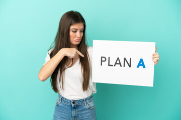 Young caucasian woman isolated on blue background holding a placard with the message PLAN A and  pointing it