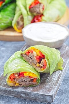 Closeup cut of beef and vegetable cabbage leaves wraps, served with plain yogurt, vertical