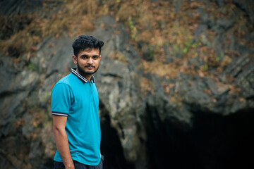 Young indian man wearing blue t-shirt standing in a cave.