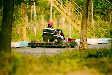Young Indian man driving go kart on the road in the park.