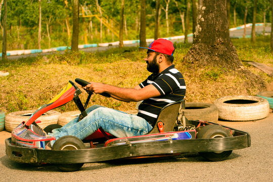 Indian man driving go kart on the road in the park.