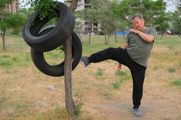 A 60-year-old Asian man is engaged in Thai boxing in nature. The concept of a healthy lifestyle.