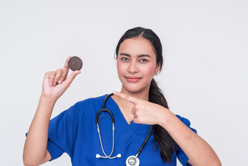 Young Asian female nurse in blue scrubs advises against eating a cookie, promoting diabetes...