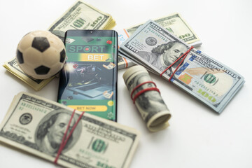 Smartphone with gambling mobile application and soccer ball with money close-up. Sport and betting...