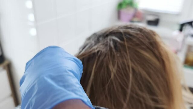 Blonde attraktive Frau, die sich Haarfarbe mit einem Pinsel auftr&auml;gt