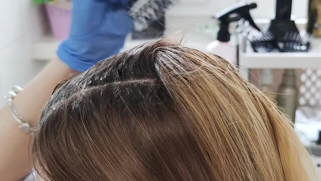 Blonde attraktive Frau, die sich Haarfarbe mit einem Pinsel auftr&auml;gt