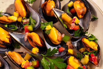 Steam cooked mussels with Vinaigrette garnish on beige plate, top view, Mediterranean cuisine.