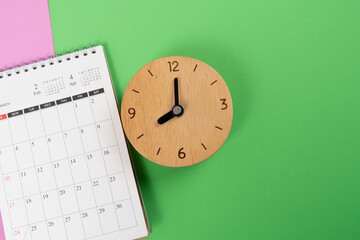 close up of alarm clock and calendar on the colorful table background, planning for business meeting or travel planning concept