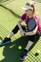 Happy female paddle tennis player during practice on outdoor court looking at camera. Copy space.