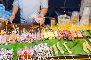 Bustling street food stall showcases skewered delicacies, from tantalizing seafood to traditional meats, ready to entice passersby with aromatic, grilled treats. Street food and small business concept - obrazy, fototapety, plakaty