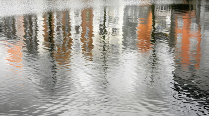 A buildings reflection is seen in the water, creating a mirror image of the structure against the rippling surface