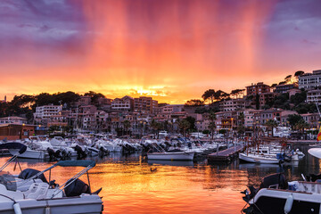 Port de Soller at sunset. Beautiful twilight shining at rainy clouds. Harbor with boats at travel destination in Mallorca, Spain