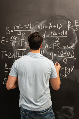 Physics teacher writes various formulas on the blackboard	