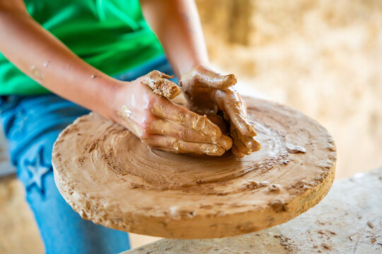 Close up view of potter hands, teen makes ceramic pot on a potter's circle 