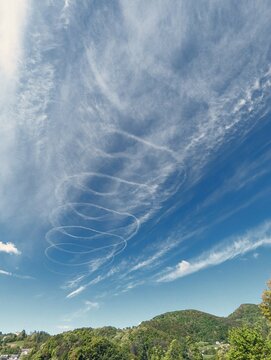 Blue sky with chemtrails from air plane, contrails, nature background, spiral shaped clouds