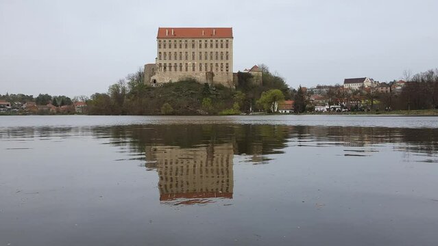 Historical Plumlov castle from 17th century and reflection on the surface of the pond in Prostejov district in Czech republic. Cloudy smoke fog air pollution sky.