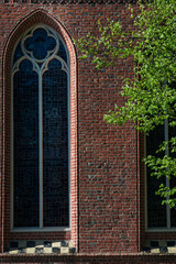 Vertical window with a stained glass window of a red brick Gothic church 