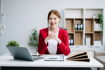 Confident Asian woman with a smile standing holding notepad and tablet at the ffice..