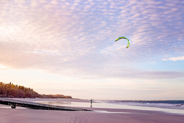 kite surfer sunset beach, boat ramp, ocean water reflections, clouds pink tones.  Adventure...