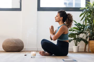 Foto op Plexiglas Sporty young woman doing yoga and hypopressive exercises while staying in lotus position in living room at home. © nenetus