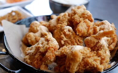 Snowy cheese Korean fried chicken on a black plate.
