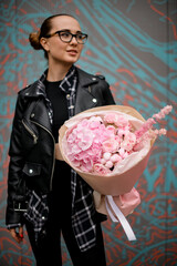 Young pretty woman holding a bouquet of pink hydrangeas with roses wrapped in kraft paper