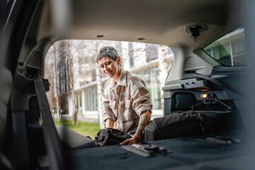 one senior woman pack luggage baggage suitcase in the trunk of the car