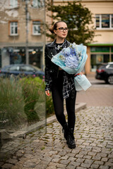 Young attractive girl holding a flower arrangement of blue hydrangeas and other flowers