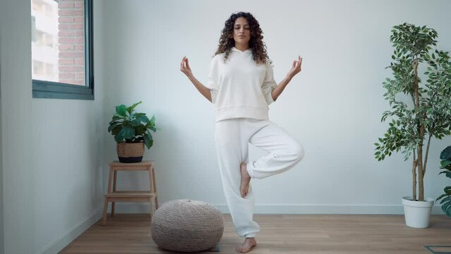 Video of zen peaceful woman dressed in a white tracksuit doing yoga poses in the studio