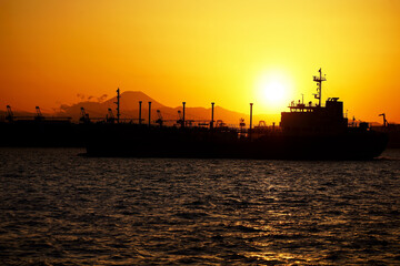 夕陽が照らす東京港を出港する貨物船