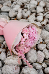 A bouquet of pink roses with pink hydrangeas lies on small stones