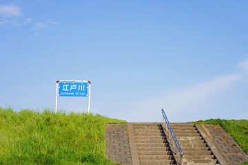 江戸川の土手に続く道と春の午後の青空
