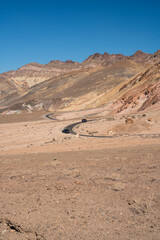 A road winds through a desert with a blue sky overhead