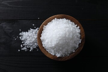 Organic salt in bowl on black wooden table, top view