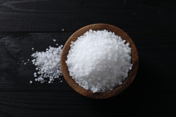 Fototapeta na wymiar Organic salt in bowl on black wooden table, top view